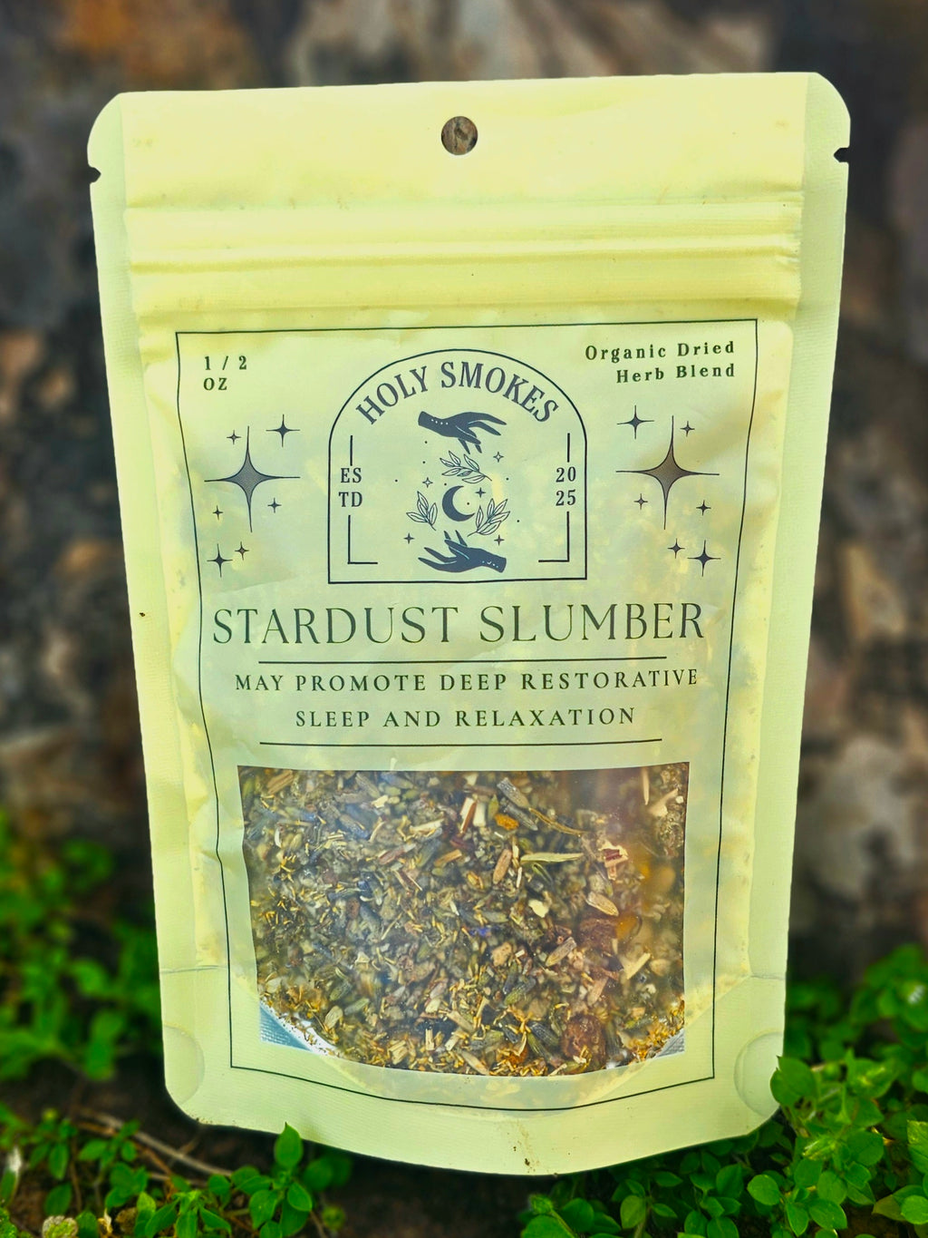 Packaged herb blend labeled 'Stardust Slumber' from Holy Smokes on a natural background.